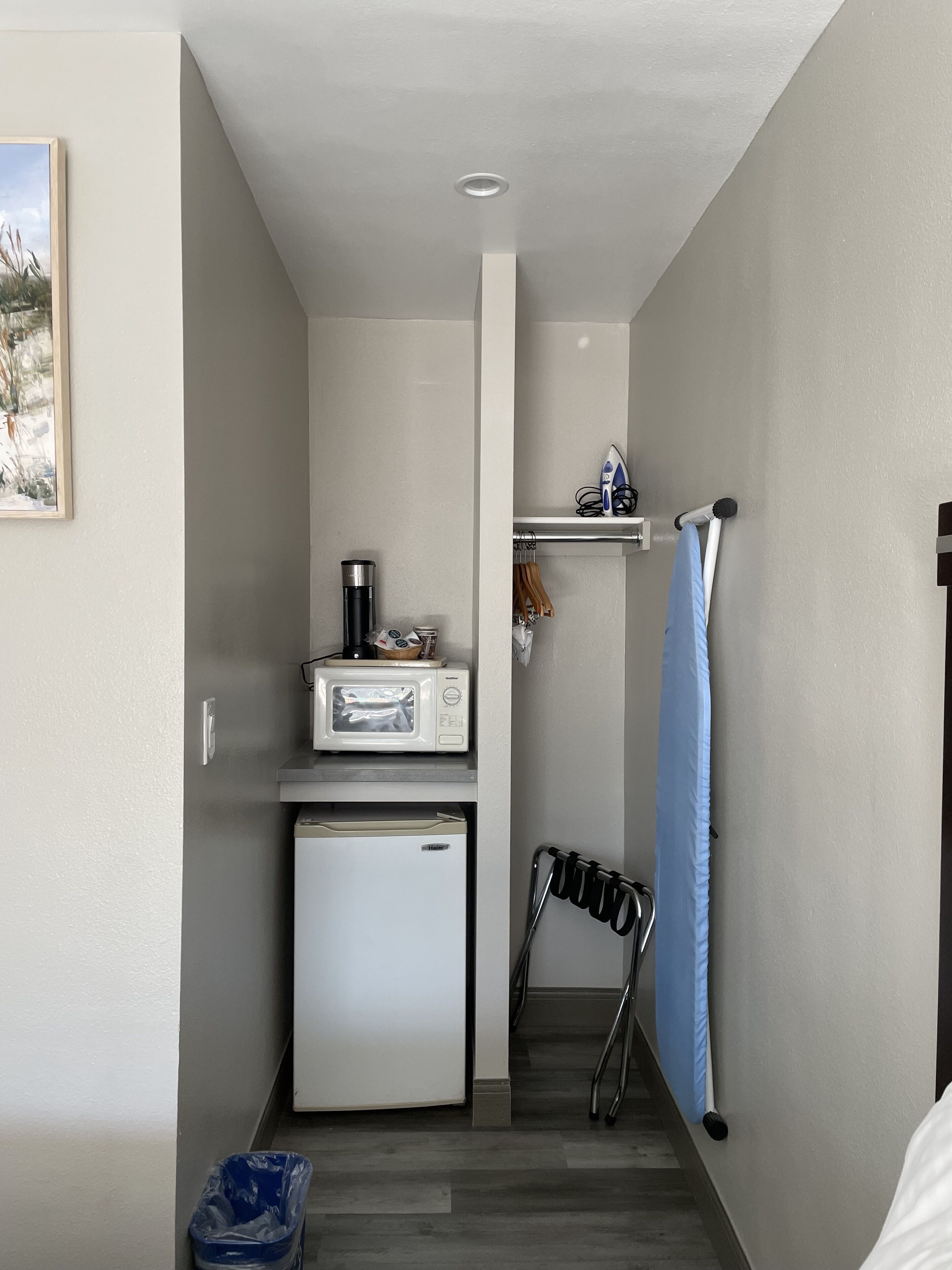 A compact kitchen with a microwave, a small refrigerator, and a coffee maker on the countertop.