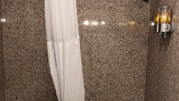 A bathroom with a bathtub, a shower, and a towel rack.