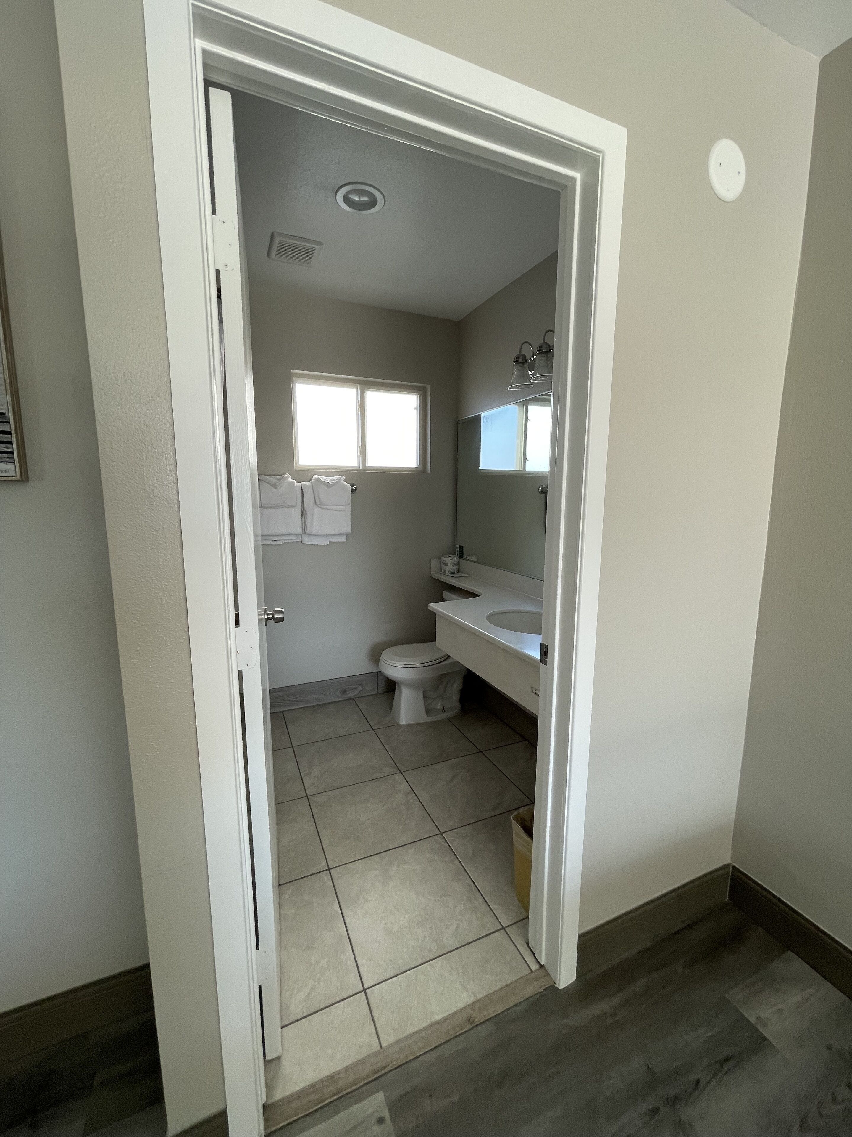 A bathroom with a toilet, sink, and window.