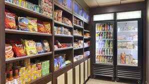 A snack aisle with shelves stocked with various chips and dips, and a refrigerated section with bottled beverages. - Country Inn & Suites by Radisson, Sandusky South, OH (Milan)