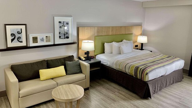 Ett hotellrum med en säng, en soffa, ett litet runt bord och väggmonterade lampor.