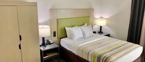 A hotel room with a bed, two bedside tables with lamps, a wardrobe, and a curtain.