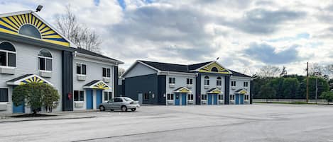 A motel with multiple rooms, a parking lot, and a clear sky.