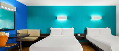 A hotel room with a bed, two bedside tables, a chair, a small table, and a wall-mounted TV.
