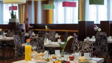 A dining area with tables set for breakfast, including plates of food, drinks, and decorative flowers.
