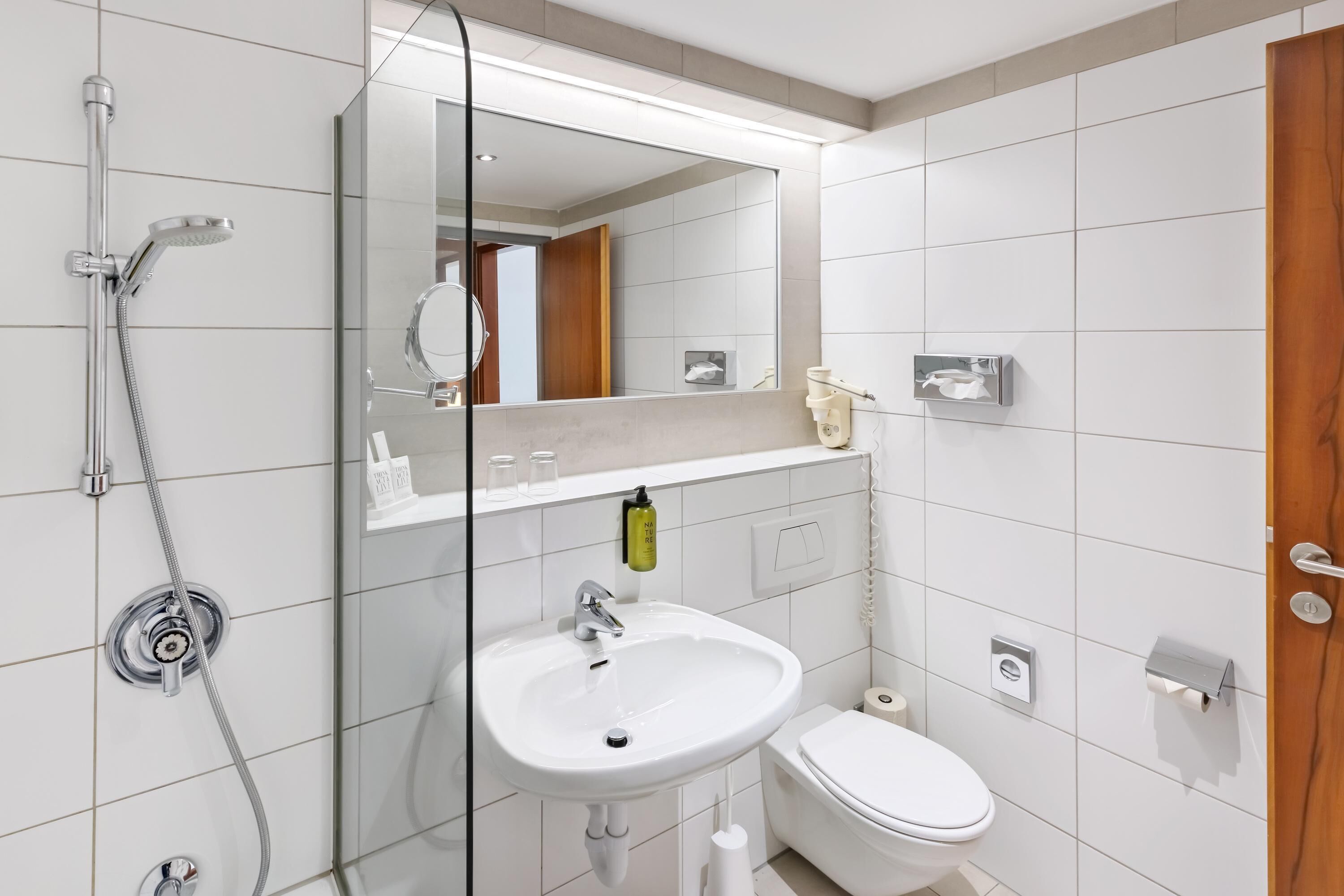 Ein modernes Badezimmer mit Duschkabine aus Glas, einem weißen Waschbecken und einer Toilette.