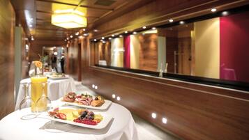 Un bufé de desayuno con diversos platos y bebidas sobre una mesa redonda en un pasillo de hotel.
