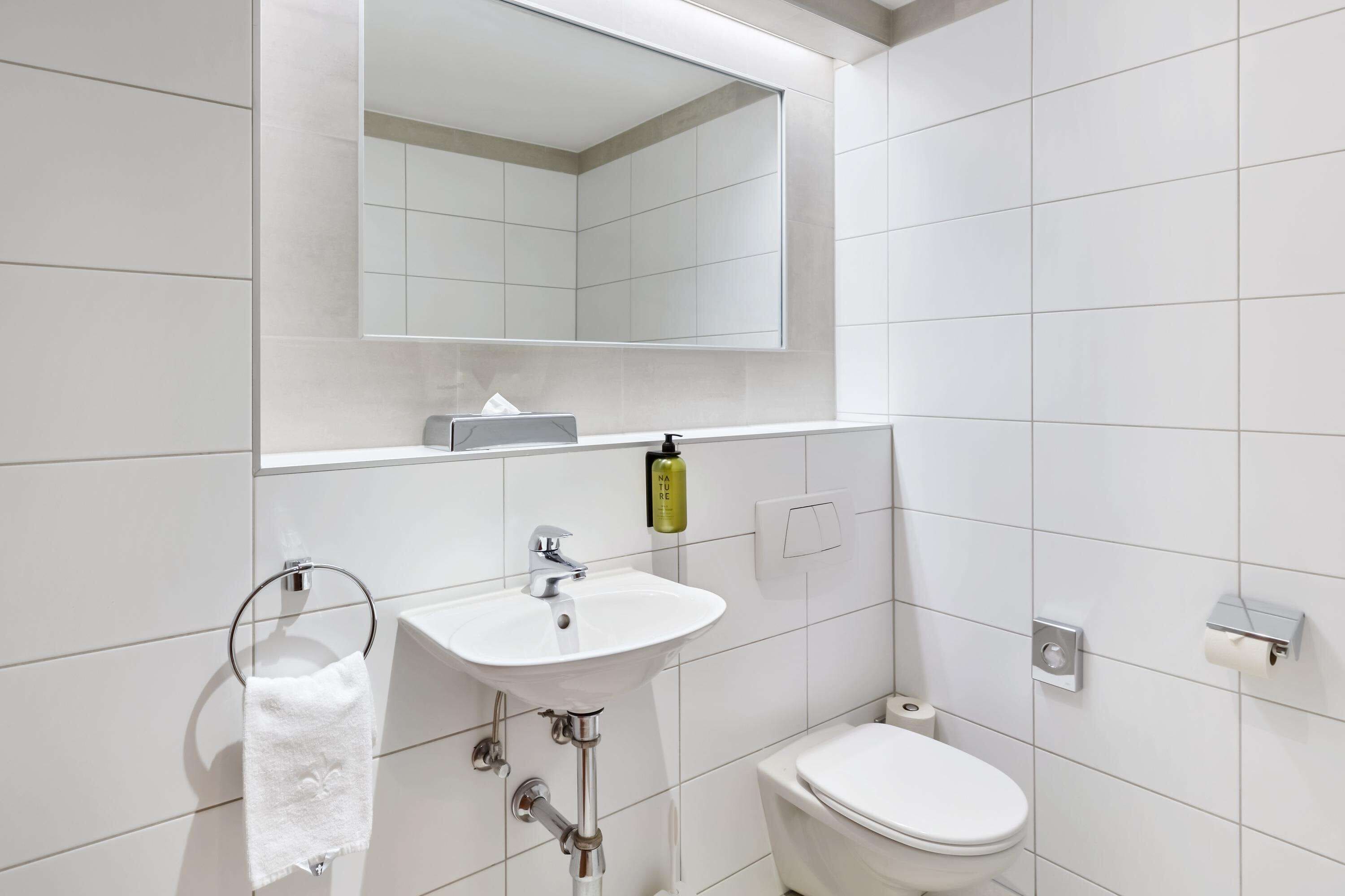 Ein modernes Badezimmer mit Waschbecken, Spiegel und Toilette in Weiß.