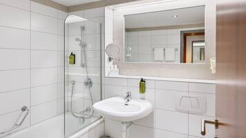 A modern bathroom with a glass-enclosed shower, a white sink, and a large mirror above the sink.