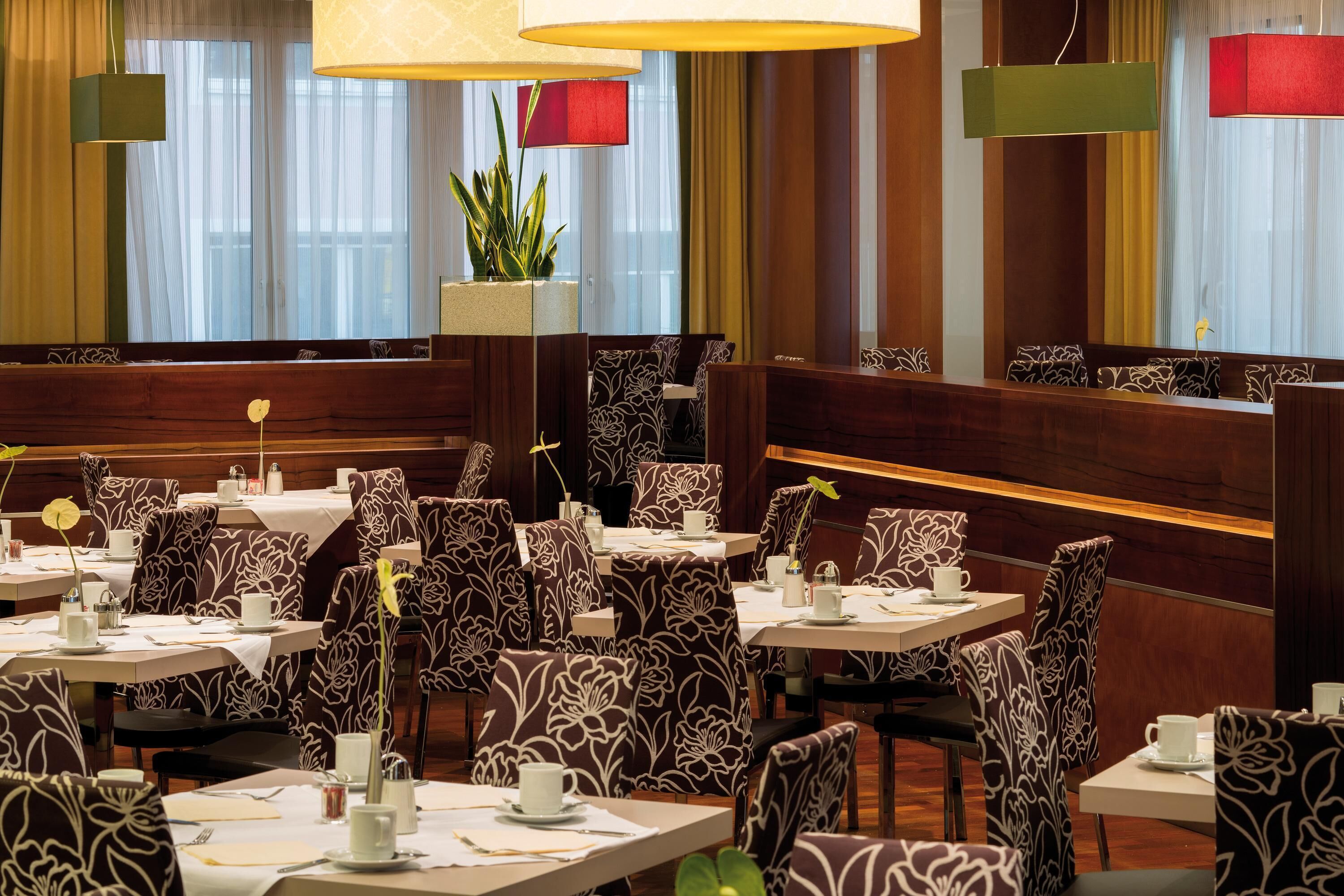 Un restaurante con cabinas y mesas, cada una con mantel blanco y sillas estampadas con motivos florales.