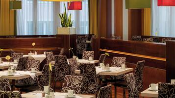 Un restaurante con cabinas y mesas, cada una con mantel blanco y sillas estampadas con motivos florales.