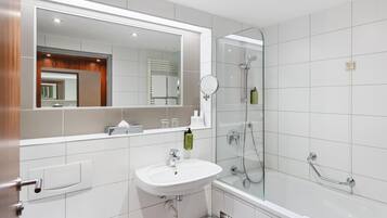 Ein modernes Badezimmer mit Waschbecken, Spiegel und Duschkabine aus Glas.
