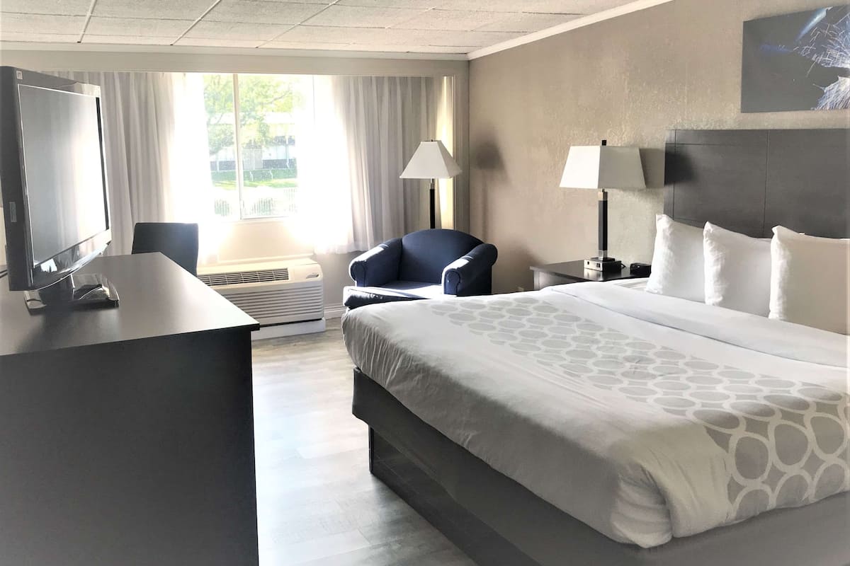 Une chambre d’hôtel équipée d’un lit, d’un bureau avec un ordinateur, d’une chaise, d’une lampe et d’un téléviseur.