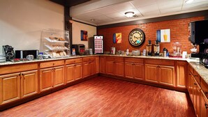 Een keuken met houten kastjes, een granieten aanrechtblad en een bakstenen muur.