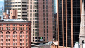 A Holiday Inn Express building with a brick facade, large windows, and a prominent tower with a spire.