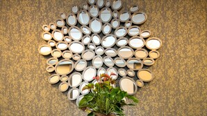 A reception area with a wooden console table, a wall-mounted mirror art piece, and a potted plant.
