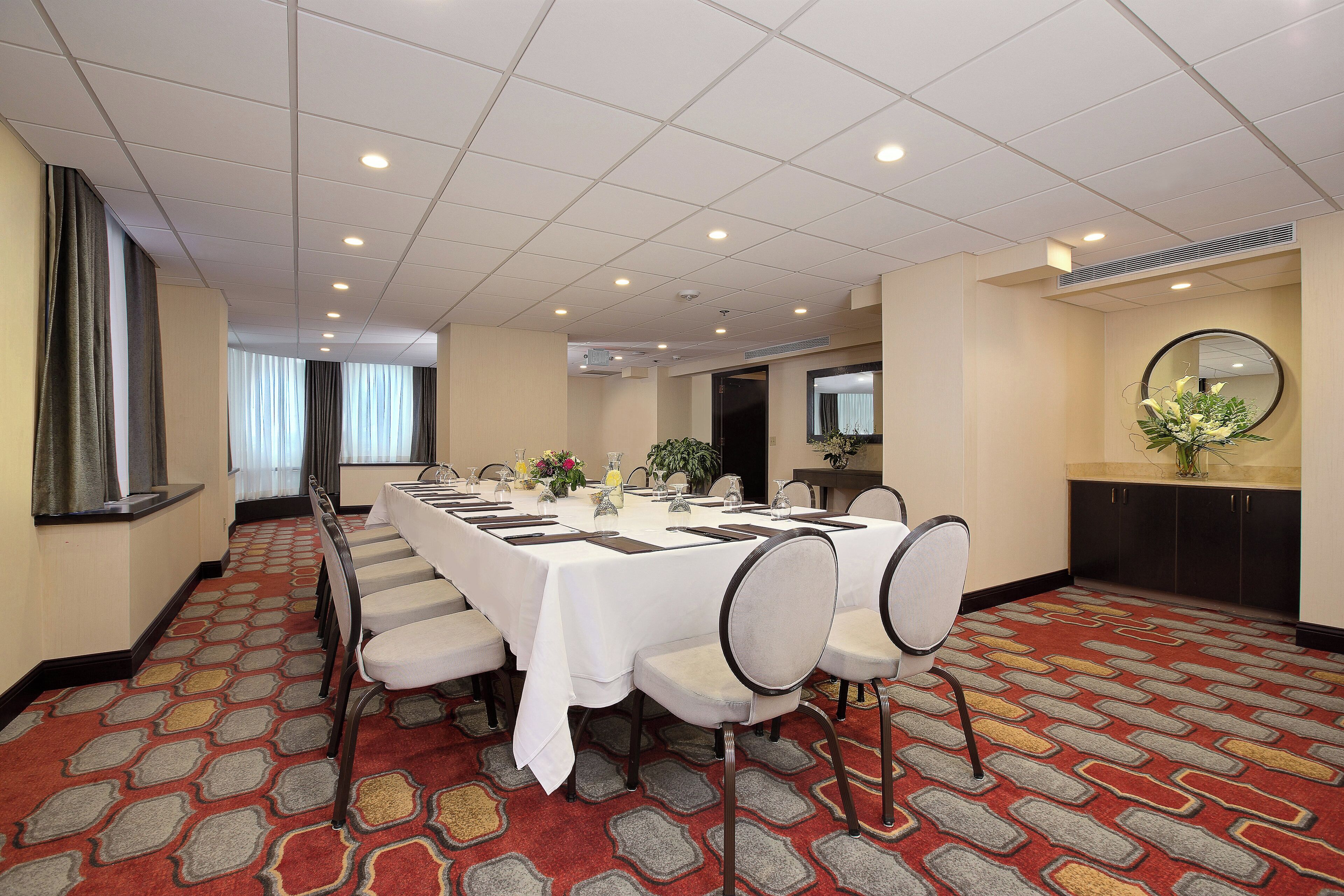 A conference room with a long table, chairs, and a carpeted floor.