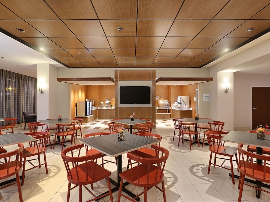 Uma sala de conferências ampla com várias mesas e cadeiras, uma televisão de tela plana grande e teto de madeira.