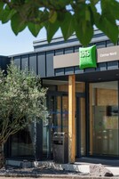 Un hotel moderno con un cartel de ibis hotels, fachada de madera y un gran ventanal.