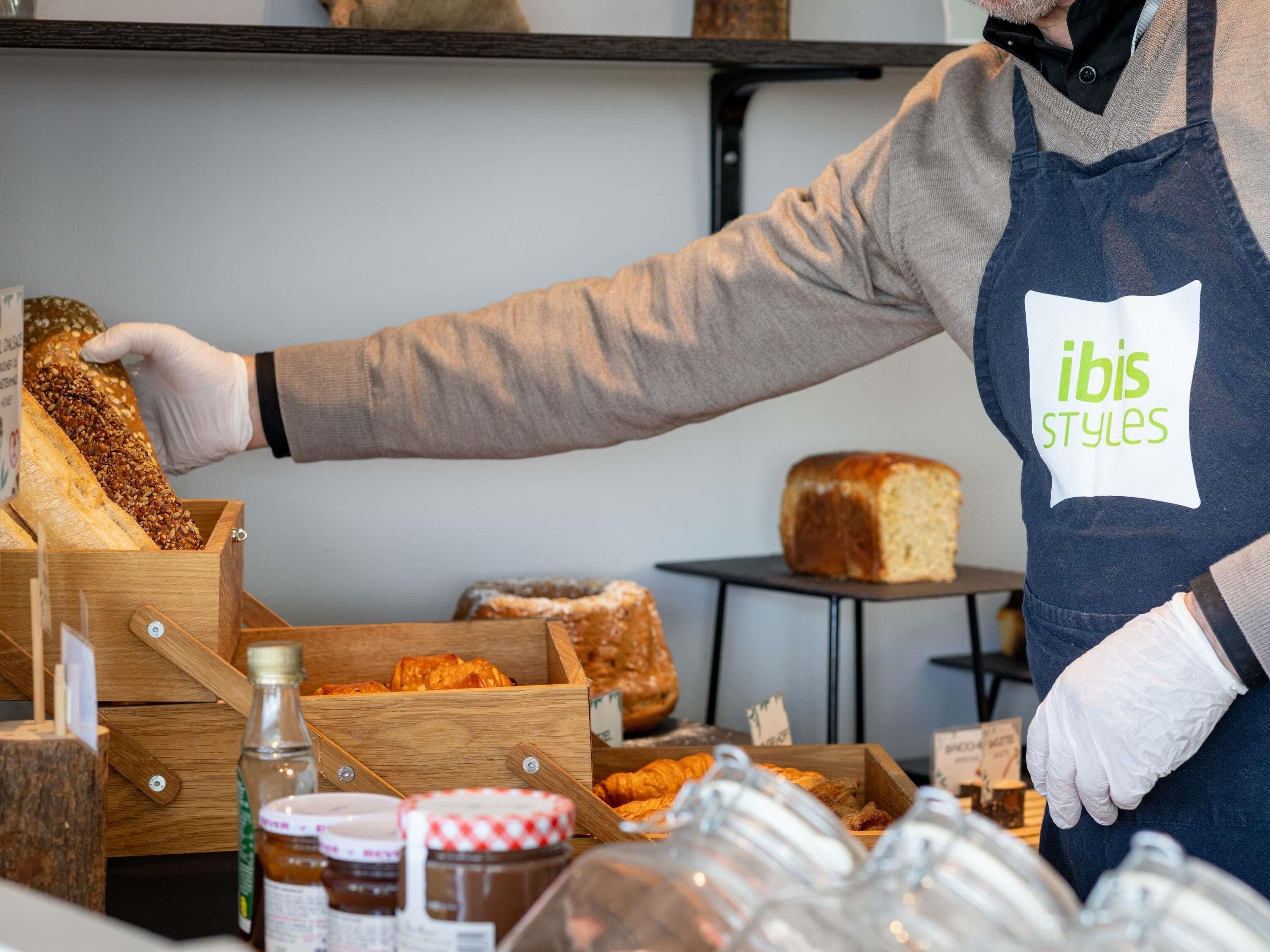 Un comptoir de boulangerie où sont exposés divers produits de boulangerie et des pots de confitures et de pâtes à tartiner.