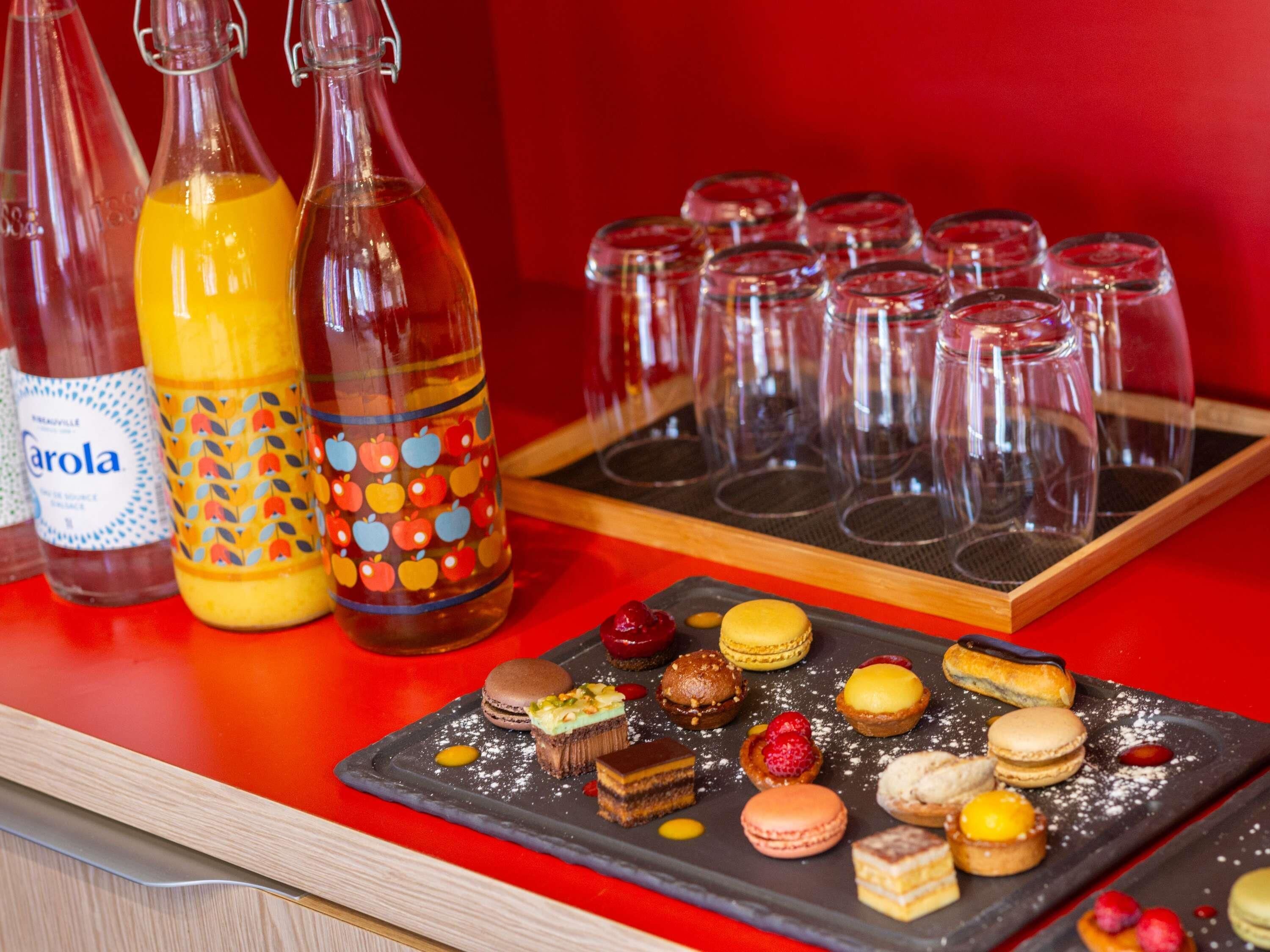 Een tafel met verschillende flessen, glazen en een schaal desserts.