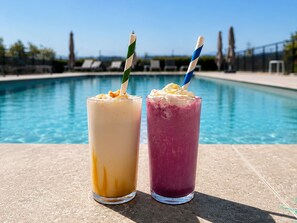 Deux boissons avec des pailles, posées devant une piscine.