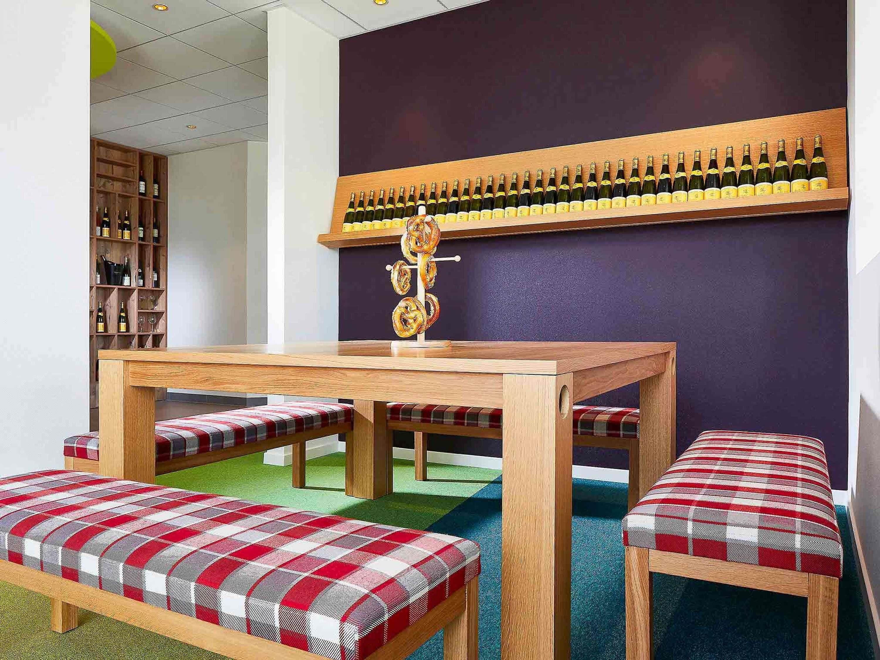 A room with a wooden table, benches, a wall-mounted wine rack, and a bookshelf.