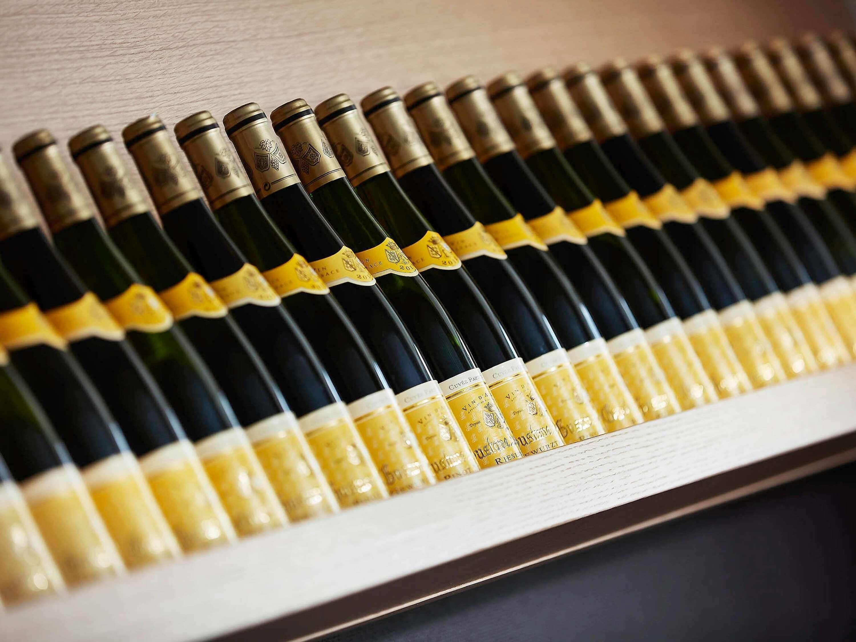 A row of wine bottles with labels, arranged in a wooden rack.