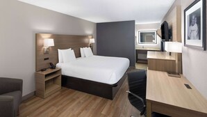 A modern hotel room with a large bed, bedside tables, a desk, and a chair. - Baymont by Wyndham Nashville (Nashville)