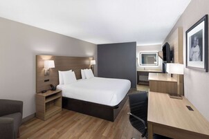 Una habitación de hotel moderna con una cama grande, mesitas de noche, un escritorio y una silla.
