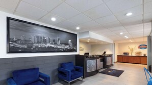 A reception area with a cityscape mural, two blue armchairs, a reception desk, and a breakfast corner. - Baymont by Wyndham Nashville (Nashville)