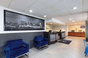 A reception area with a cityscape mural, two blue armchairs, a reception desk, and a breakfast corner.
