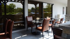 An outdoor patio with a glass table and chairs, surrounded by large windows and a stone wall. - Baymont by Wyndham Nashville (Nashville)