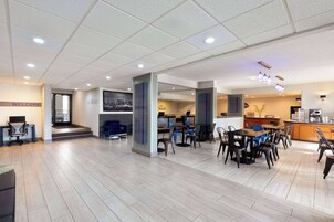 A modern office space with a reception area, meeting rooms, and a dining area with tables and chairs.