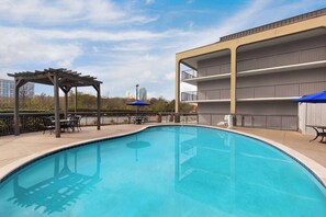 Una piscina al aire libre de temporada, sombrillas