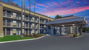 A multi-story hotel with a covered entrance, outdoor lighting, and flags. - Baymont by Wyndham Nashville (Nashville)