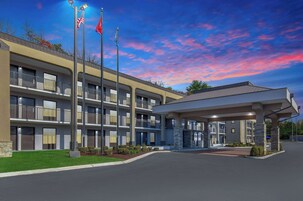 A multi-story hotel with a covered entrance, outdoor lighting, and flags.