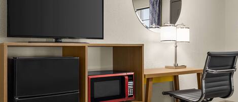 Une chambre d’hôtel équipée d’une télévision à écran plat, d’un four à micro-ondes, d’un réfrigérateur, d’un bureau avec une lampe et d’une chaise.