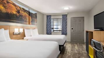 Habitación de hotel con dos camas, un ventanal con cortinas, un televisor y un armario de madera.