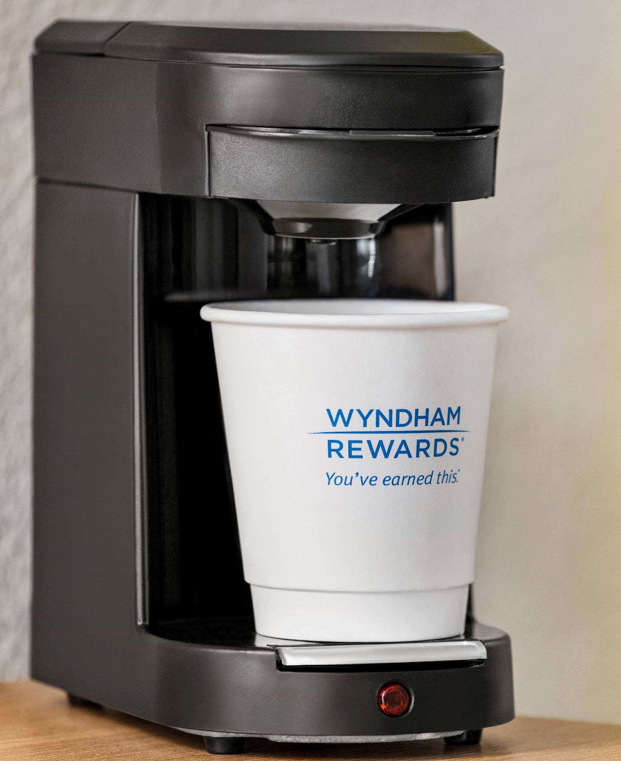 A coffee machine with a cup labeled "WYNDHAM REWARDS" and the text "You've earned this."