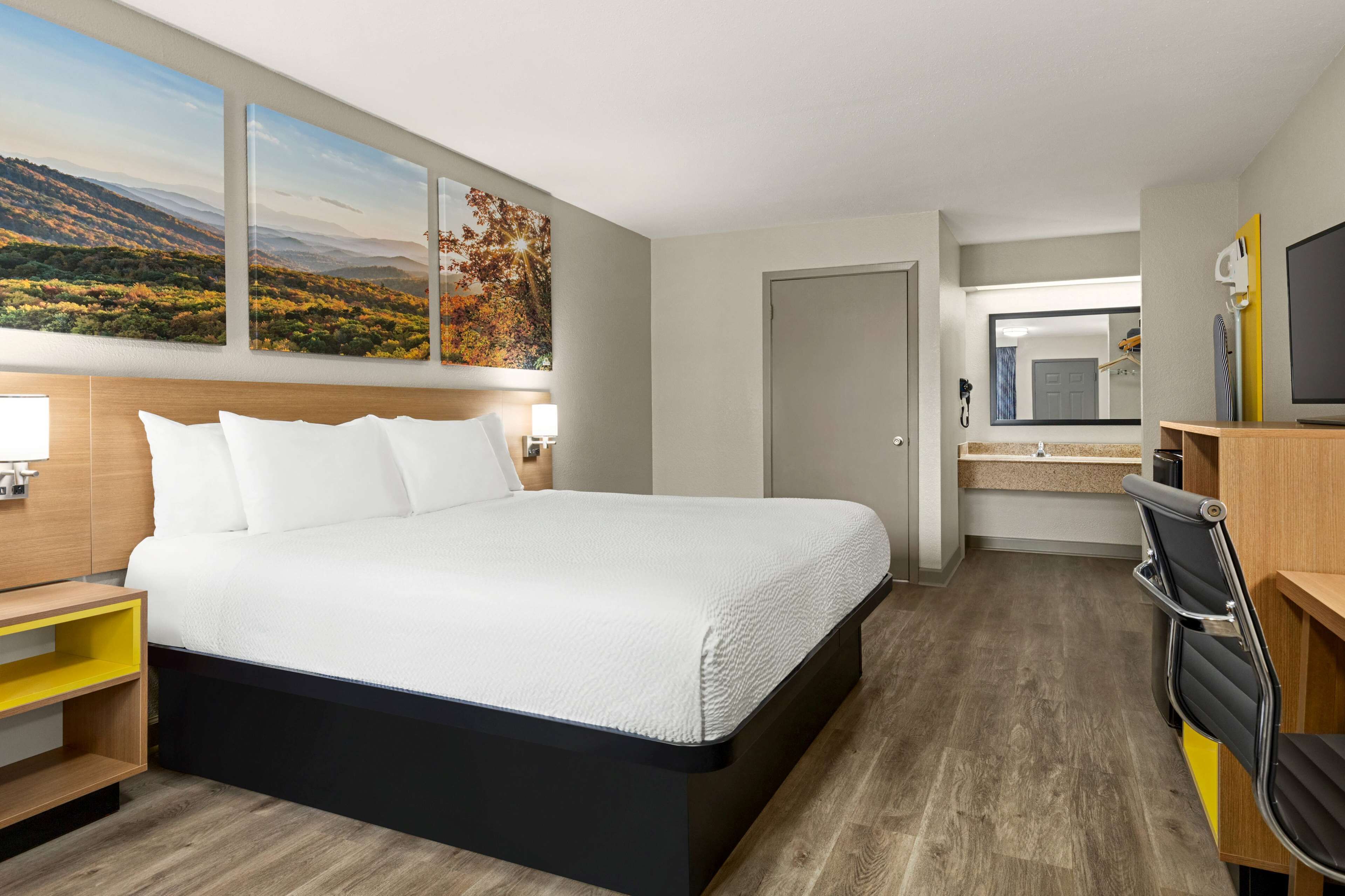 Habitación de hotel con una cama grande, un escritorio con una silla, televisión y ventana con vistas al paisaje.