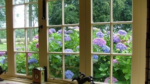 A room with a large window overlooking a garden with hydrangeas. - Esseborne Manor Hotel (Andover)