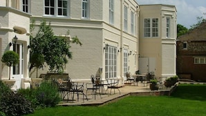 A two-story building with a white exterior, large windows, and a patio area with outdoor furniture. - Esseborne Manor Hotel (Andover)