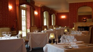 A dining area with multiple tables set for service, each with a white tablecloth, wine glasses, and cutlery. - Esseborne Manor Hotel (Andover)
