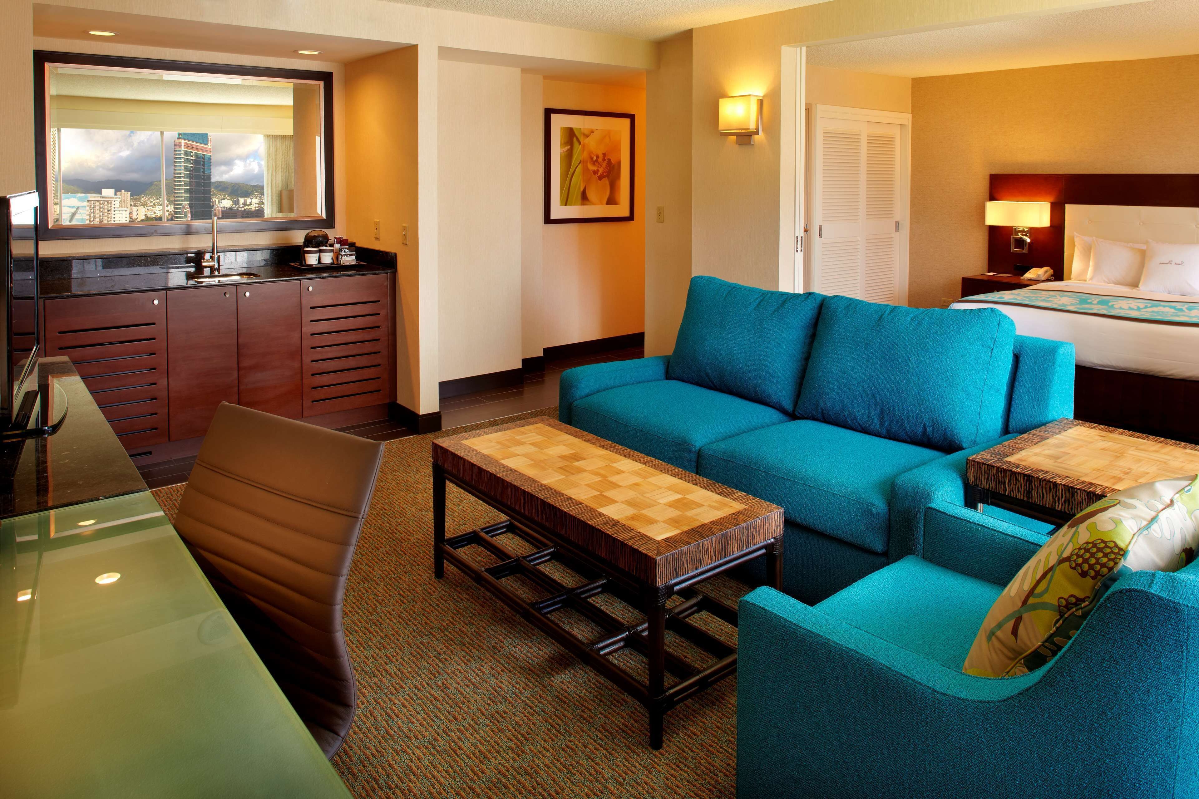 Une chambre d’hôtel avec vue sur la ville, comprenant un canapé, une table basse, un bureau et un lit.