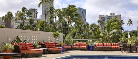 A rooftop pool area with lounge seating and palm trees.