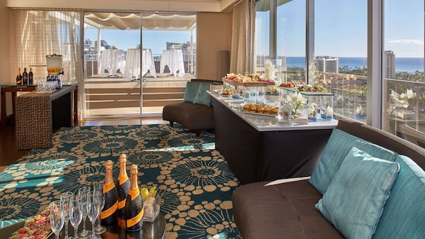 A spacious balcony with a city view, furnished with a sofa and a dining table set for a meal.