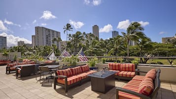 A rooftop patio with outdoor seating, including sofas and chairs, and a flagpole with flags.