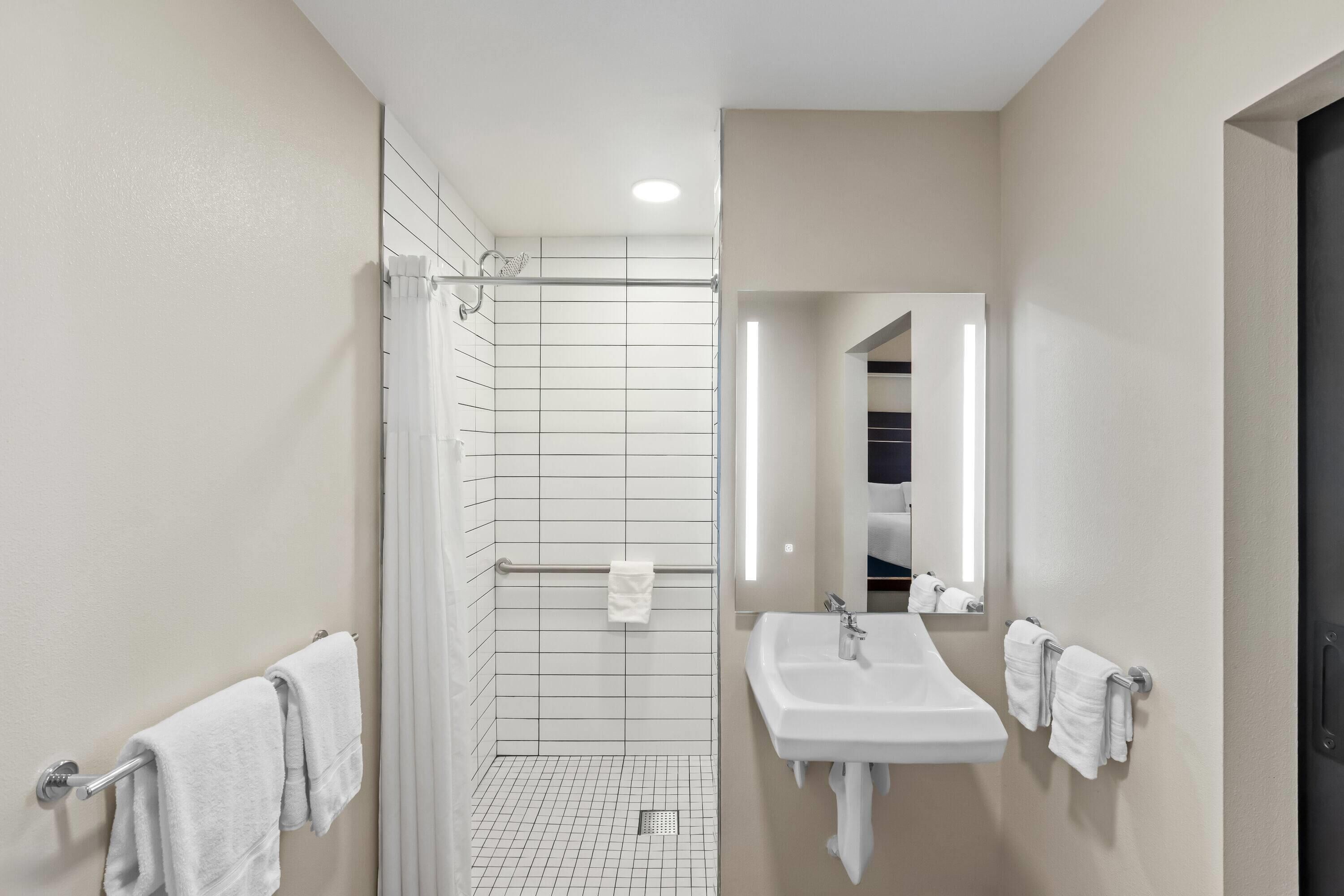 A modern bathroom with a shower, a sink, and a mirror.