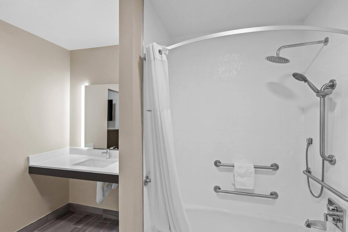 A modern bathroom with a shower, a sink, and a mirror.